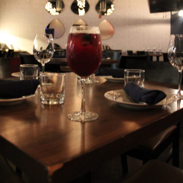 A Bar 141 table set with plates, glasses, and a red cocktail in a wine glass.