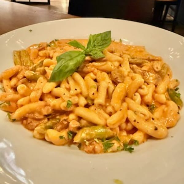 Bar 141's pasta dish with creamy sauce, green vegetables, and a basil garnish.