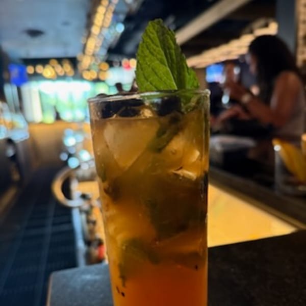 A tall glass of Bar 141's signature cocktail, garnished with mint, on a bar counter.