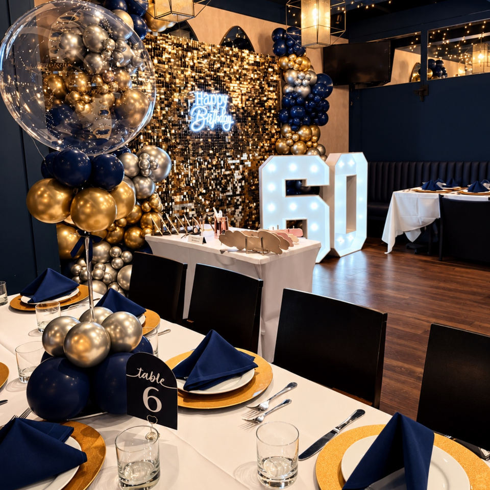 Elegant restaurant dining room decorated for a birthday celebration with navy and gold balloons, illuminated numbers, and festive table settings.