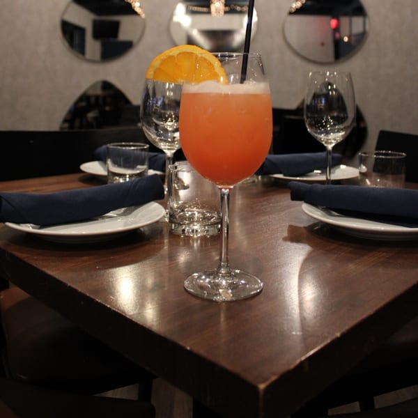 A Bar 141 table set with plates, dark blue napkins, and a vibrant orange cocktail.