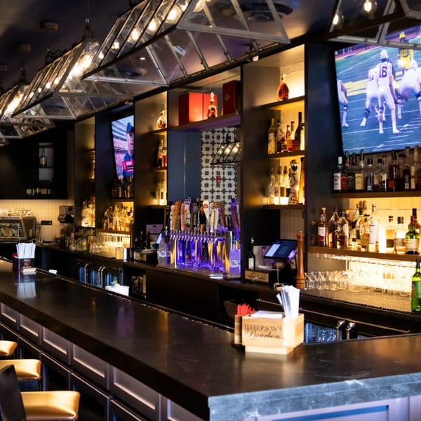 Bar 141's interior features a long, dark bar counter, liquor shelves, beer taps, and TVs showing sports.