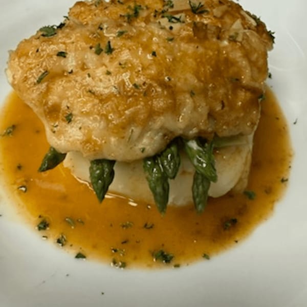Bar 141's golden-brown fish fillet with asparagus spears, drizzled with a rich orange sauce.